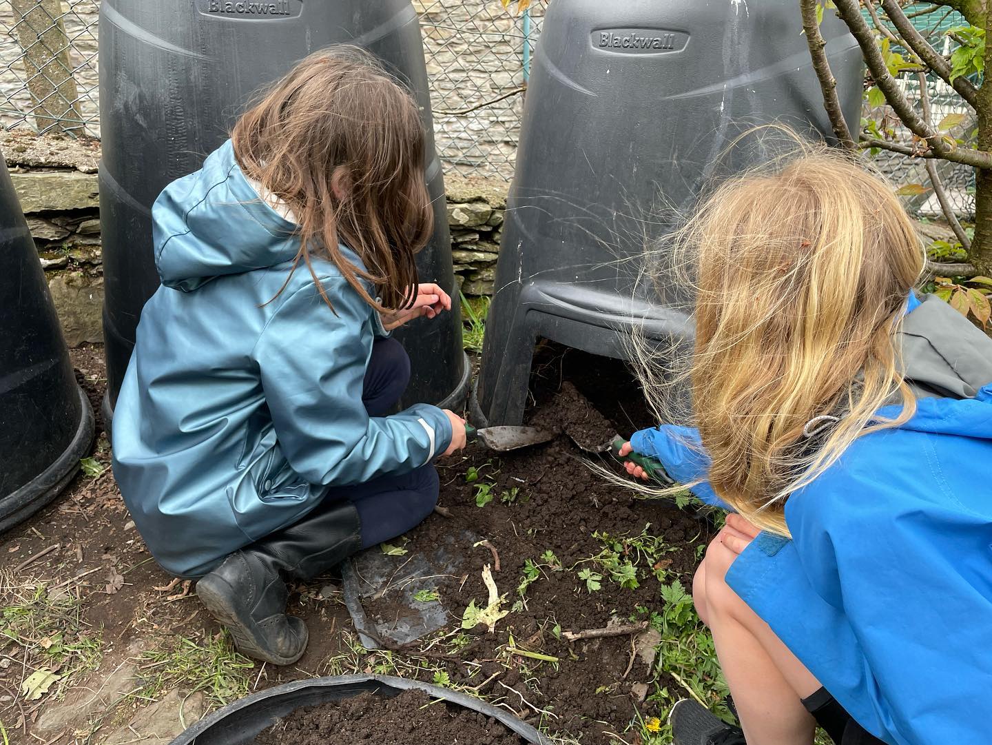 Two young girls using compost from a home compost bin.
